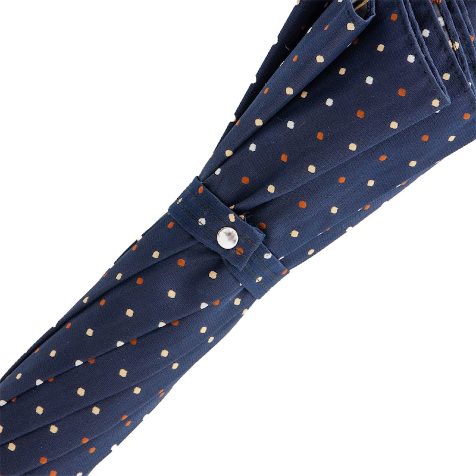 Close-up of folded navy blue umbrella with white and orange polka dots and snap closure strap