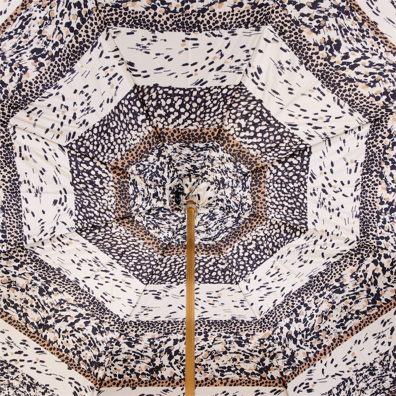 Top view of a patterned umbrella with black, white, and brown animal print designs and a wooden central pole