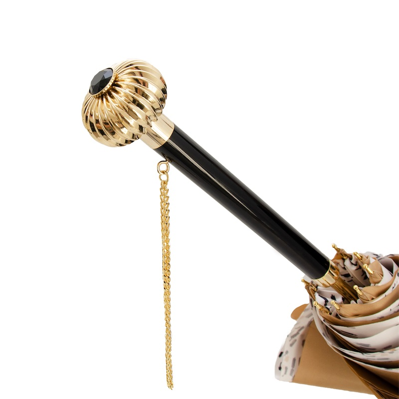 Elegant umbrella handle with gold decorative top, black shaft, and hanging gold chain detail