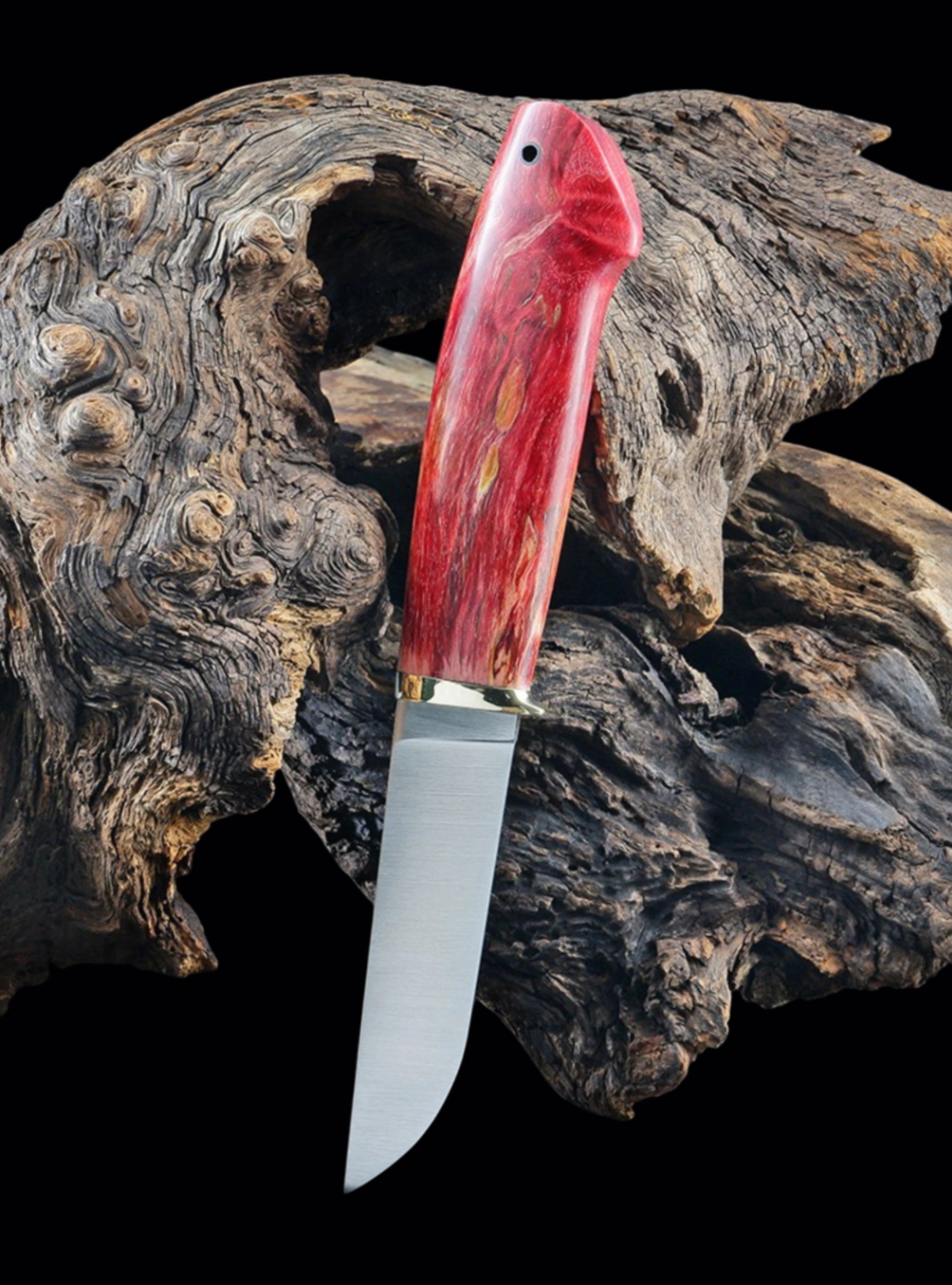 Knife with a red handle on a piece of driftwood