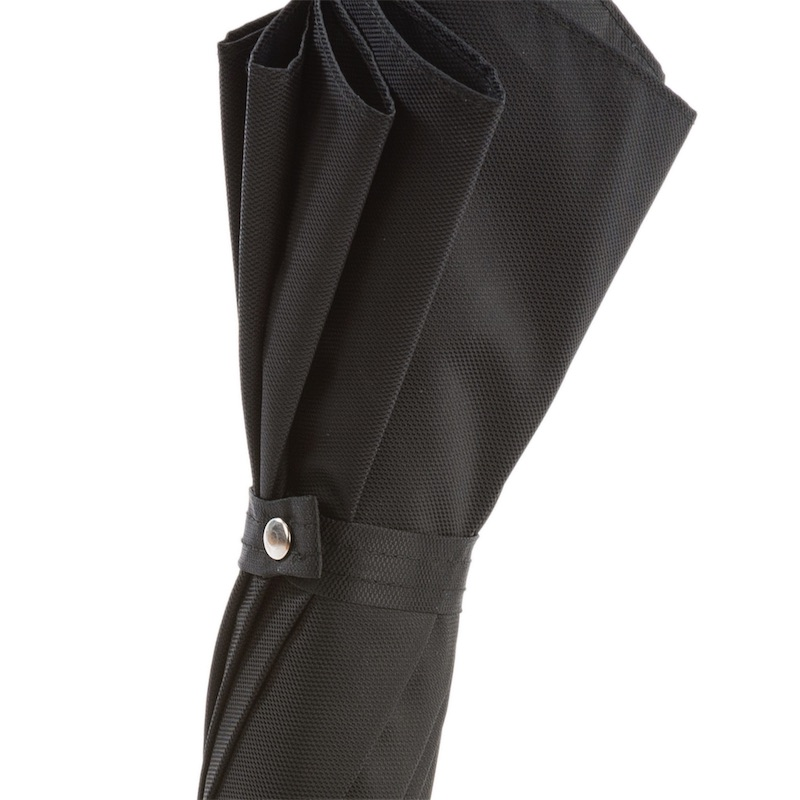Folded black textured umbrella secured with a snap button strap on white background