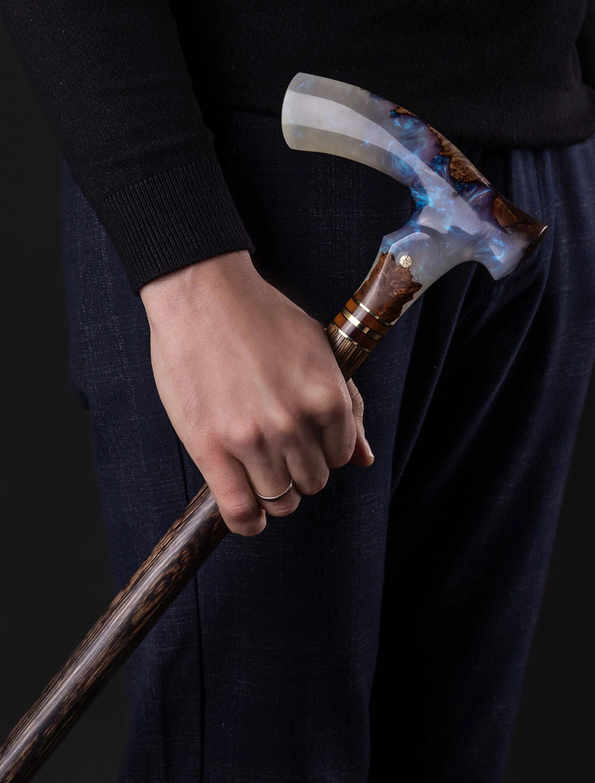 Person holding a decorative walking cane with a dark background